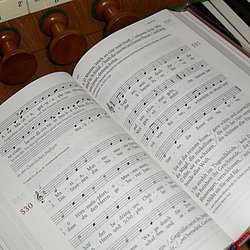 Das Bild zeigt ein Gotteslob, das auf den Tasten einer Orgel liegt. 